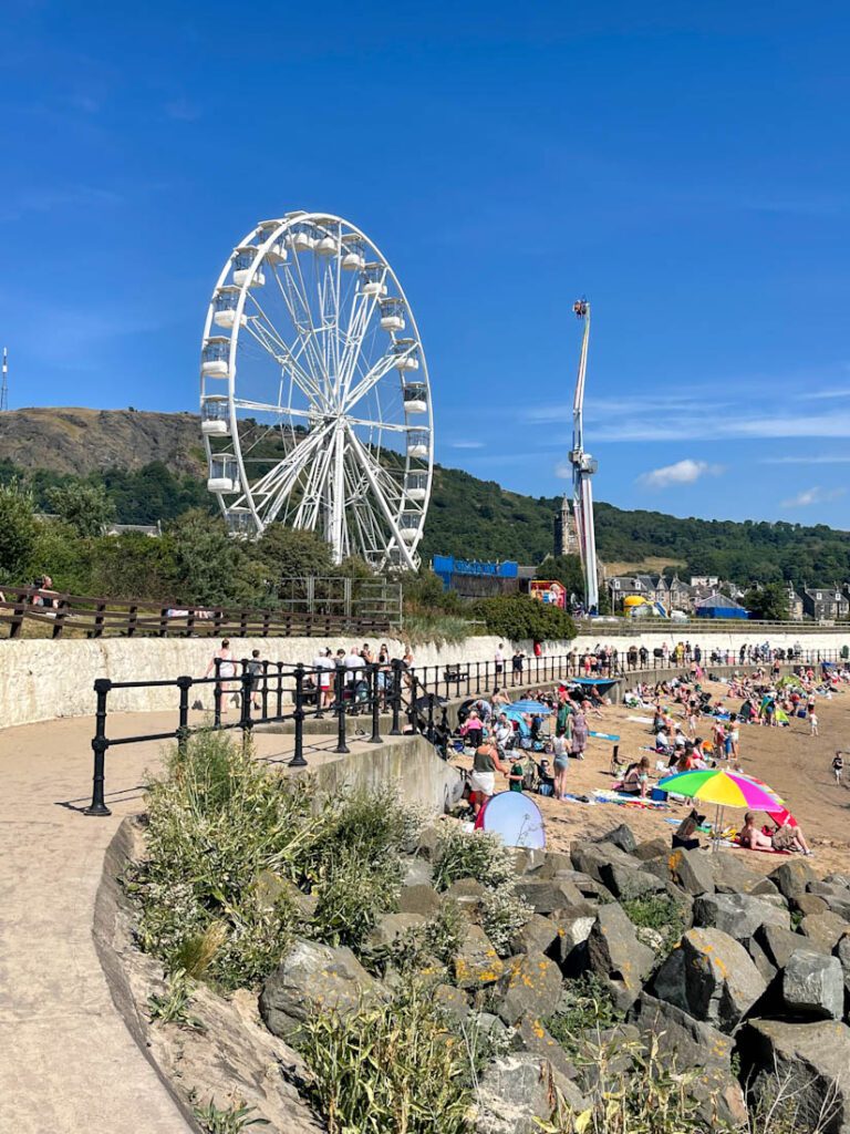 Busy Burntisland Beach in Fife with fairground and blue skies in the background