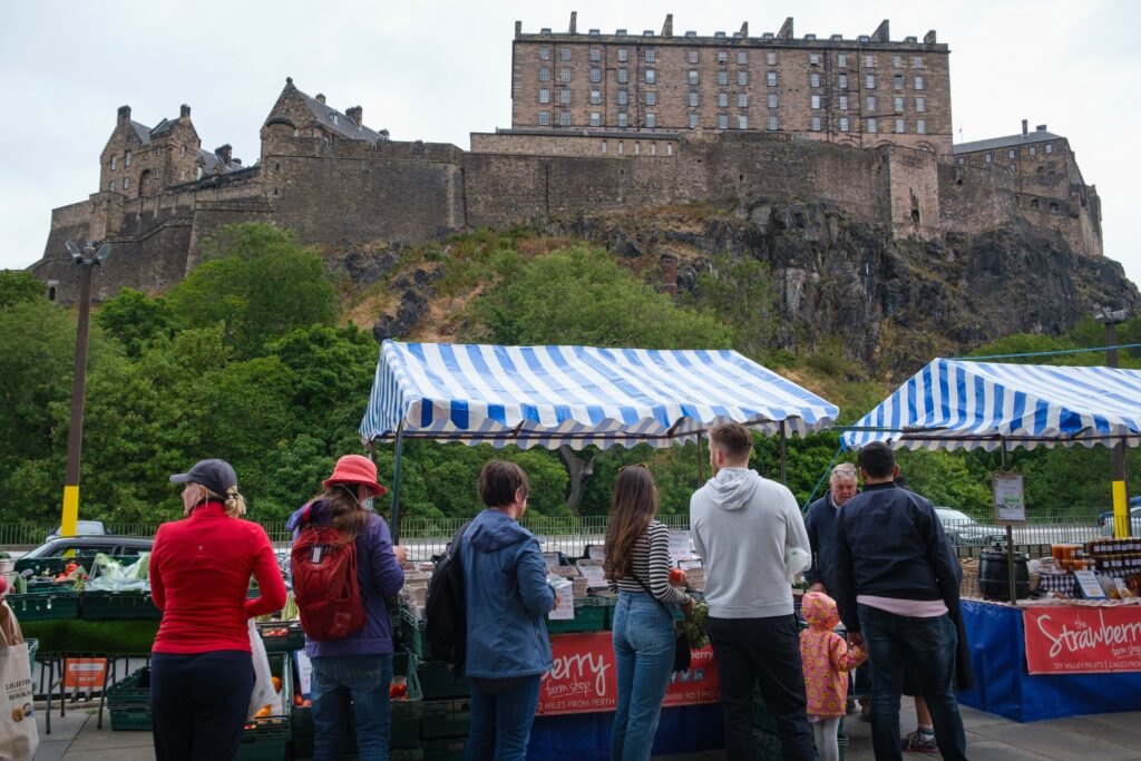 Edinburgh Farmers Market fresh produce stalls with a stunning view of Edinburgh Castle in the background