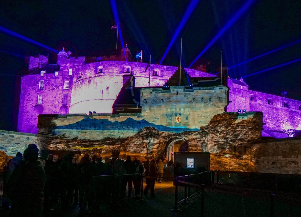 edinburgh castle of light from the front of the castle with purple glow and light beams coming out of the top