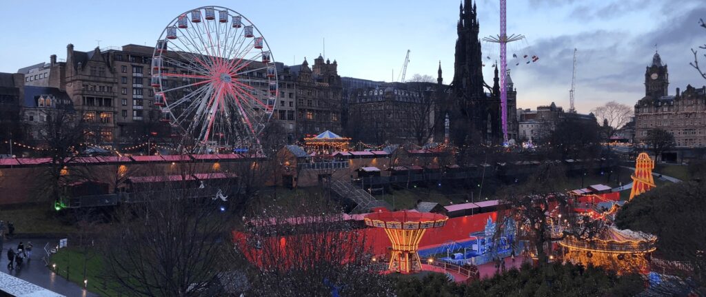 view across edinburgh christmas market, ferris wheel and star flyer lookinng towards princes street