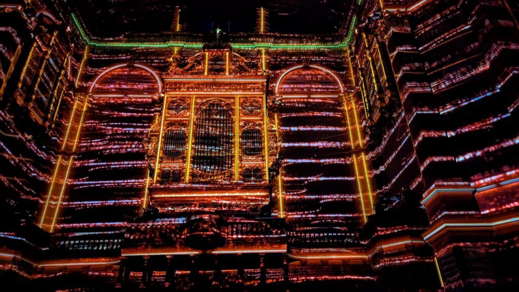 red and orange lights projected onto the wall of edinburgh mcewan hall in the shape of the building