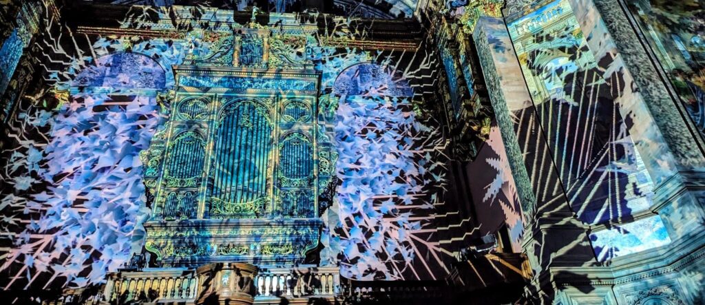 enlightenment edinburgh mcewan hall display - blue, green and white projections on the front wall highlighting the organ