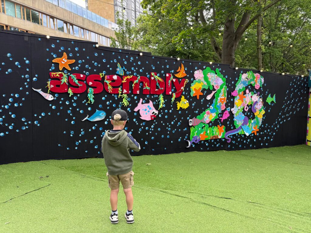 little boy with his back to the camera look at the edinburgh fringe assembly 26 sign